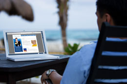 Guy on beach with laptop to Sofa Ink Quarterly